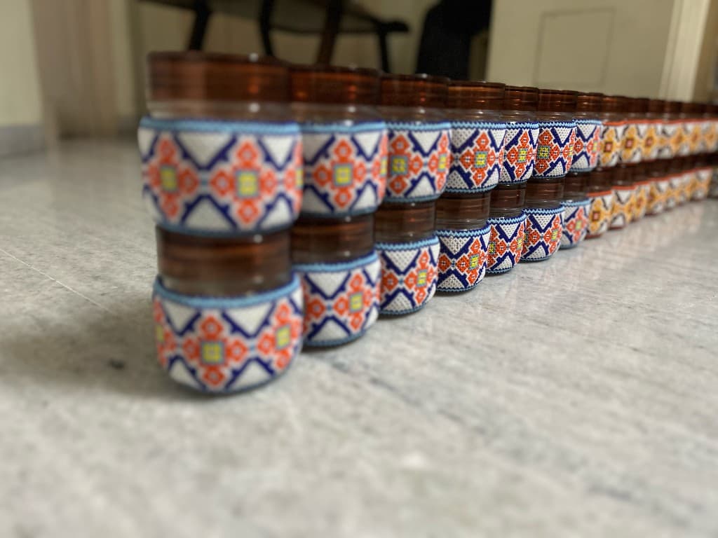 Orange and brown beaded jar held in hand warm autumn tones close up