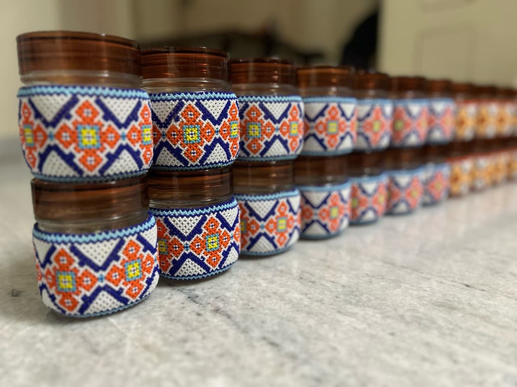 Chocolate brown and gold beaded jar held in hand, full pattern visible