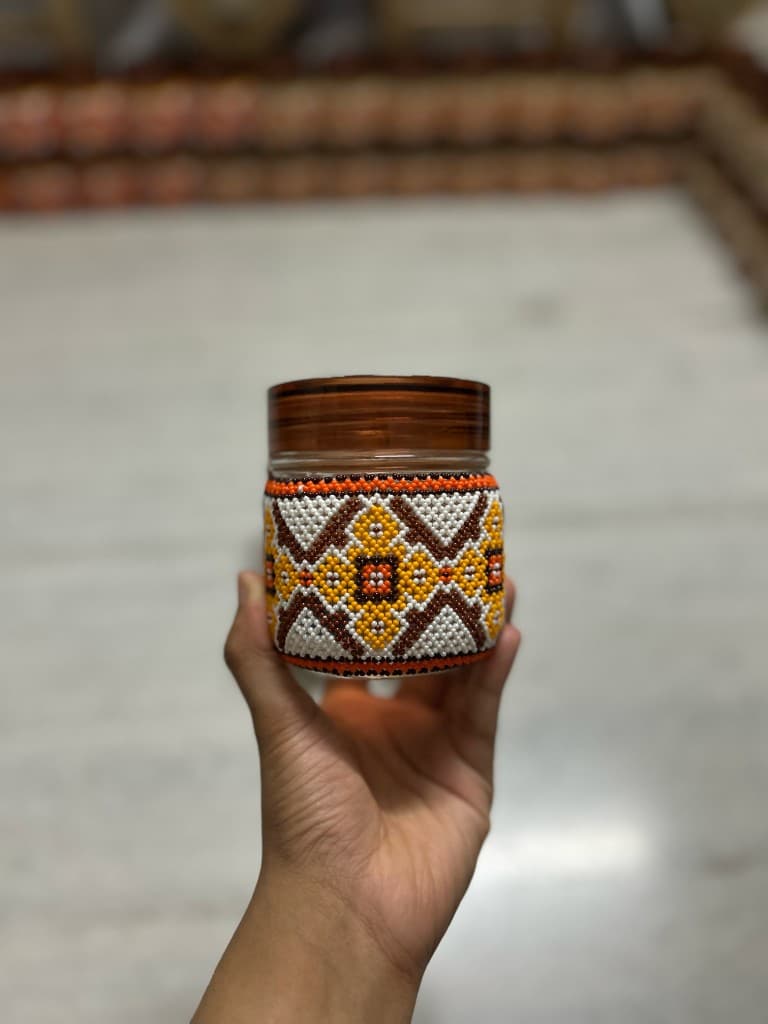 Electric blue and orange beaded jar held in hand star motif at centre