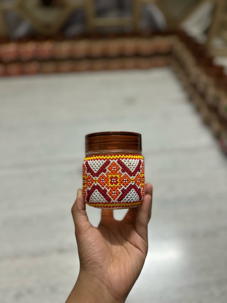 Red blue and yellow tricolour beaded jar held in hand
