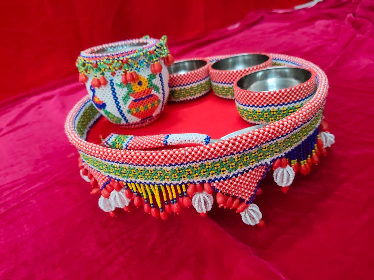 Colourful beaded matka set with intricate geometric patterns on red background