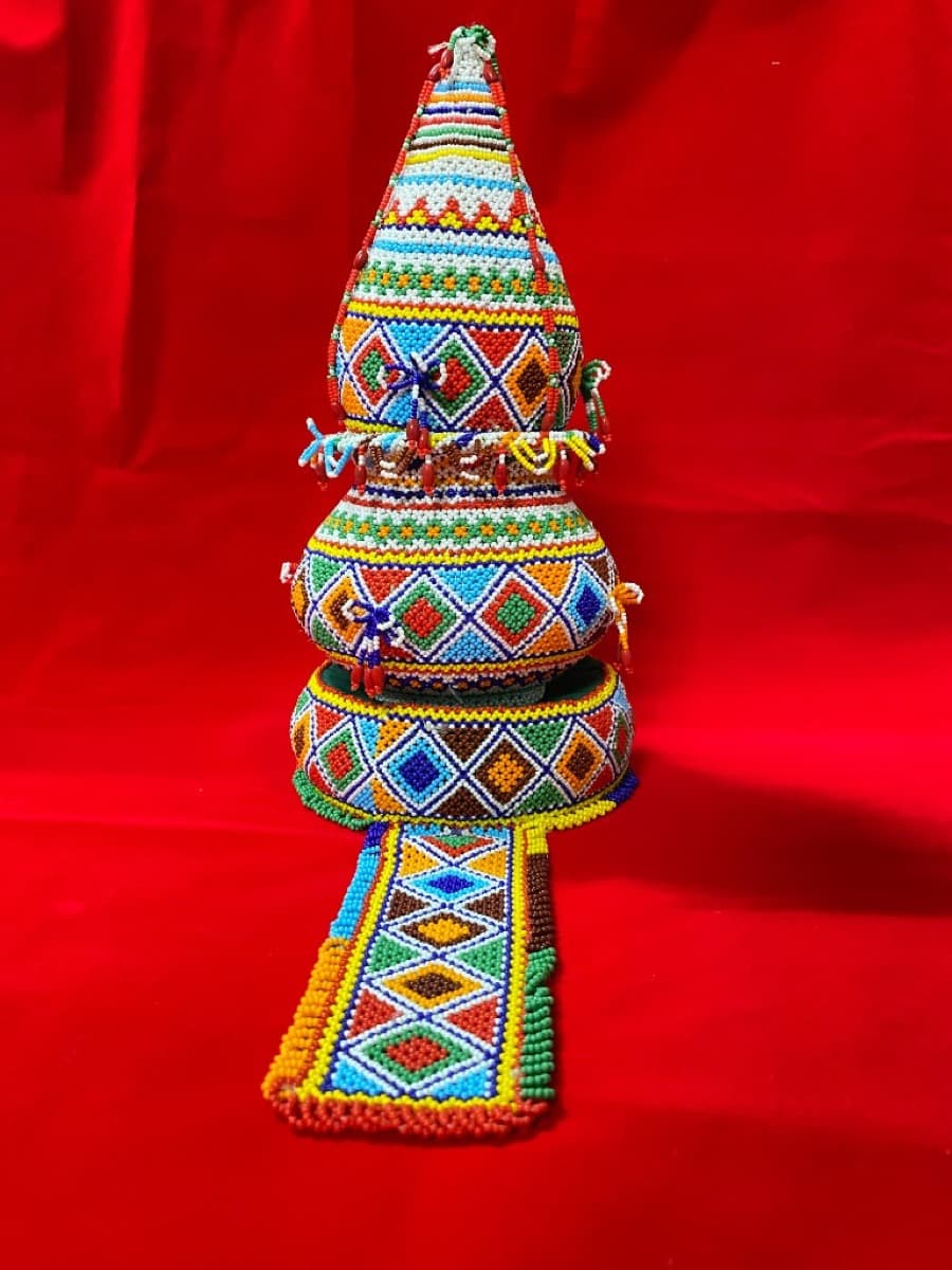Stacked moti bharat loti shrifal with pointed top, covered in colourful diamond pattern beadwork, with a beaded runner