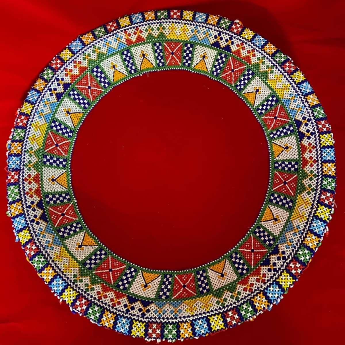 Circular beaded tras viewed from above with vibrant geometric beadwork in red, blue, green, yellow, and white